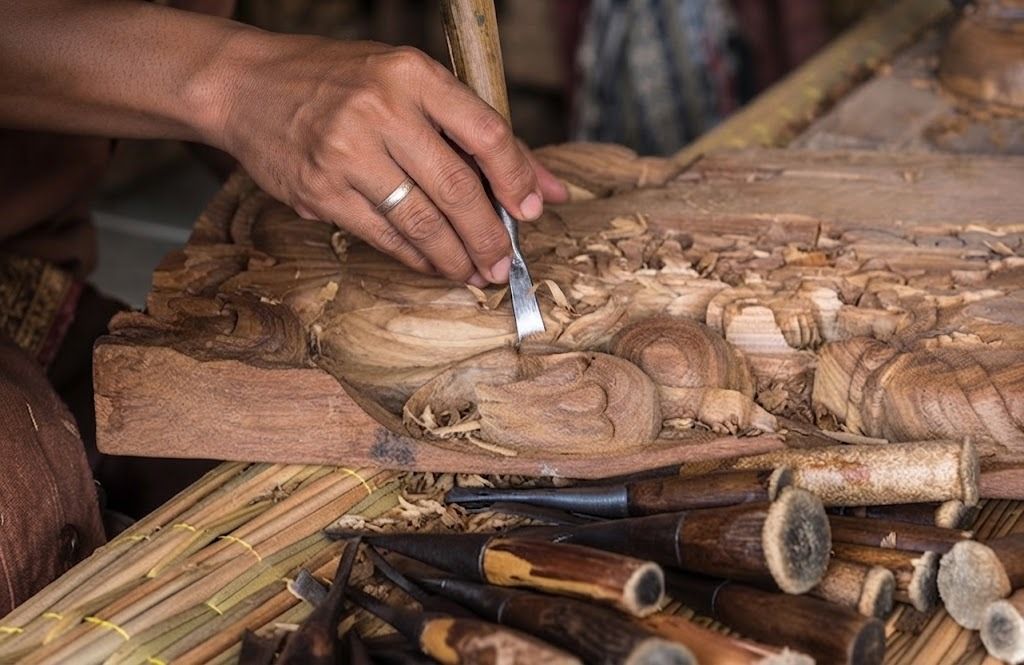 Artisan hand-carving an intricate wooden panel with traditional chisels